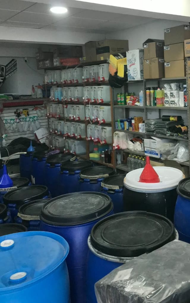 La bodega: tambos, embudo de llenado y un muro de garrafas con llave dosificadora.